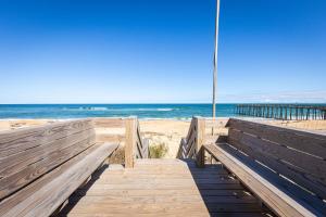 a wooden boardwalk to the beach with a pier at Oceanfront Private Beach Access & Community Pool in Kitty Hawk Beach