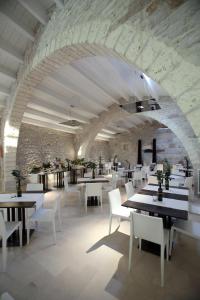 een restaurant met tafels en witte stoelen en een stenen muur bij Masseria Torre Di Nebbia in Castel del Monte