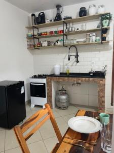 a kitchen with a stove and a table and a chair at KitNet em Caraíva-Nova Caraíva in Caraíva