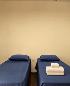 Studio Privativo 3 min Centro para 4 pessoas com 2 quartos ar condicionado في أبرلانديا: سريران عليهما ملاءات زرقاء ومناشف