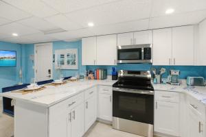 a kitchen with white cabinets and a black stove top oven at Sand Dollar Suite by Sun Palace Vacations in Fort Myers Beach