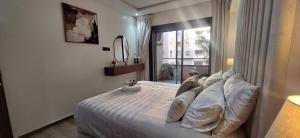 a bedroom with a bed with pillows and a window at Appartement Moderne Poolside Gueliz centre Sun PS4 & Wi-Fi in Marrakesh +12 photos