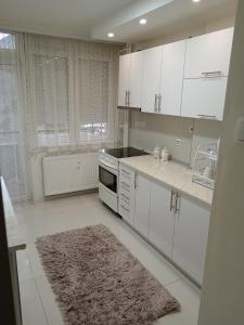 cocina blanca con armarios blancos y alfombra en Apartman Centar 2, en Šabac