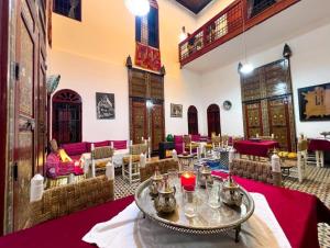 a restaurant with tables and chairs and a woman sitting in a room at Riad Dar Iman in Fès +43 photos