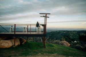 a person sitting on a cross on top of a mountain at A Cozy Fireside Glamping Escape with Ridge Views in Fallbrook