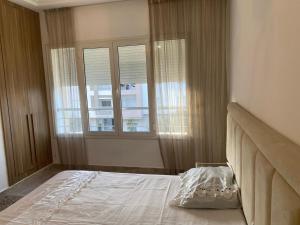 a bedroom with a bed and two windows at Luxe & Sérénité Sahloul 4 in Sousse