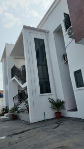 a white house with a door and a balcony at White Orchid Inn in Ibadan