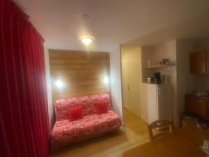 Les toits de dévoluy في لو ديفولي: غرفة معيشة مع أريكة حمراء مع وسائد حمراء