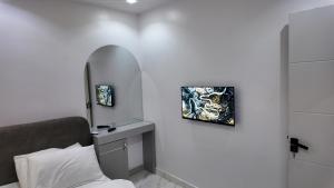 a white room with a bed and a mirror at White Orchid Inn in Ibadan