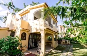 a house with a palm tree in front of it at Caribbean DELUXE VILLAS Los CORALES beach, POOL & SPA in Punta Cana