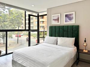 a bedroom with a large bed with a green headboard at EspacioYa By Mario Rental Calle 100 in Bogotá +251 photos