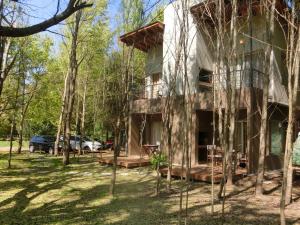 une maison dans les bois avec des arbres devant elle dans l'établissement Complejo Aires del Bosque, à Chascomús