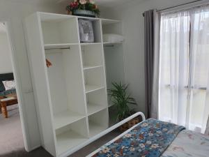 a white book shelf in a room with a bed at Cozy Home Style Accommodation in Marong
