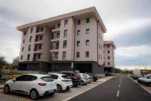 een groot wit gebouw met auto's geparkeerd op een parkeerplaats bij Pro-Link Podgorica in Podgorica