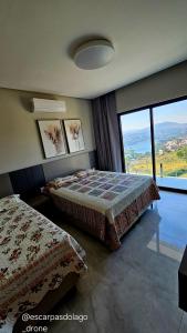 a bedroom with two beds and a large window at Casa Amaral in Capitólio