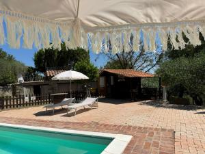 a house with a swimming pool and a umbrella at Locazione turistica ex Le Casette Di Cedromonte in Panicale