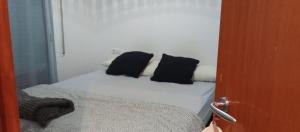 Una cama con dos almohadas negras encima. en Amali, en Blanes