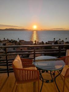 una mesa y sillas en un balcón con vistas a la puesta de sol en The Manga Beach Sea view Studio, Sandy beach & Crystal clear water, 5G Wifi & Airco, en La Manga del Mar Menor