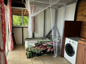 a bedroom with a bed and a washing machine at Bungalow studio in Raiatea