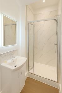 een witte badkamer met douche en wastafel bij The Miles Arms Hotel in Avonmouth