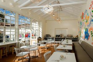a restaurant with white tables and chairs and windows at 7 Toritos Hotel Boutique by Hacienda in Cusco