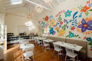 a restaurant with white tables and chairs and a colorful wall at 7 Toritos Hotel Boutique by Hacienda in Cusco