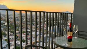 uma mesa com uma garrafa de vinho e 2 copos numa varanda em Estilo Minimalista frente Arena y Parque Fundidora em Monterrey