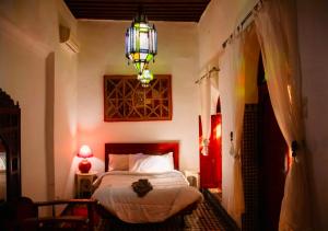 a bedroom with a bed and a chandelier at Riad Iman in Fès