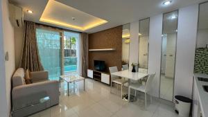 a living room with a couch and a table and a television at Amazon Condo, Building B, ground floor with direct pool access in Jomtien Beach