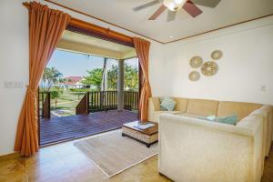 a living room with a couch and a sliding glass door at Hopkins Bay Belize a Muy'Ono Resort in Hopkins
