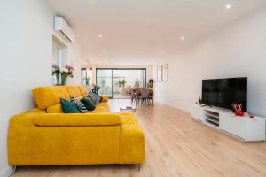 a living room with a yellow couch and a flat screen tv at Casa Butterfly in Faro