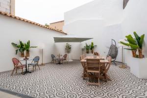 Un patio con mesas y sillas y una sombrilla. en Casa De Mariposas Viola, en Faro