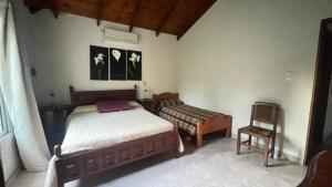 een slaapkamer met twee bedden en een stoel erin bij Casa Quinta Metac-Calle Entre Rios y Sarmiento in Villa Lía