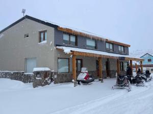 een huis in de sneeuw met motoren ervoor geparkeerd bij Black Hills Caviahue in Caviahue