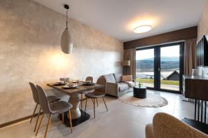 a dining room and living room with a table and chairs at Apartament Lake&Hill View w Karkonoszach z możliwym dostępem do strefy WELLNESS w kompleksie in Sosnówka