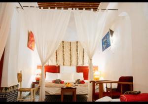 a bedroom with a canopy bed with white curtains at Riad Iman in Fès