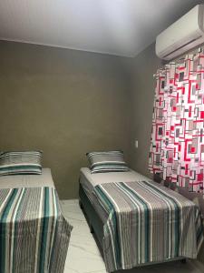 a bedroom with two beds with striped sheets at Casa providencial in São Miguel dos Milagres