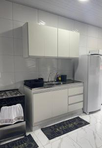 a white kitchen with a sink and a refrigerator at Casa providencial in São Miguel dos Milagres