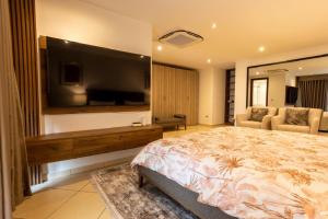 ein Schlafzimmer mit großem Bett und Flachbildfernseher in der Unterkunft KAYs APARTMENT in Accra