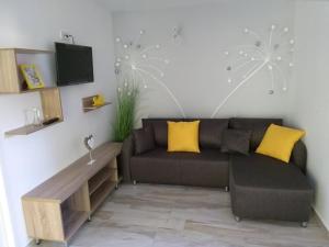 a living room with a brown couch and yellow pillows at Arapartman in Zamárdi