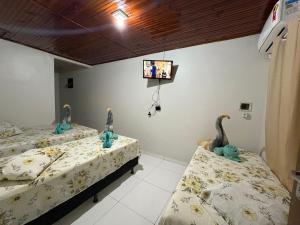 two beds in a room with a tv on the wall at Residencial Filhos da Lua in Lençóis