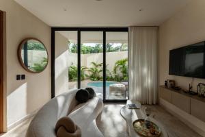 un soggiorno con divano bianco e piscina di Oniric Condo Tulum a Tulum