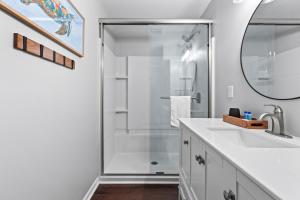 a white bathroom with a shower and a sink at 2017 Marsh Walk Villa in Summerville +25 photos
