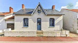 een wit huis met een blauwe deur bij Villa Floreal in Saint-Gilles-Croix-de-Vie