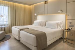 a hotel room with two beds and a table at NH Collection Lisboa Liberdade in Lisbon +50 photos