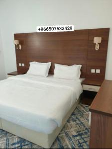 een slaapkamer met een groot wit bed met een houten hoofdeinde bij شقق سانتوريني الخاصة Santorini Private Apartments in Al Ula