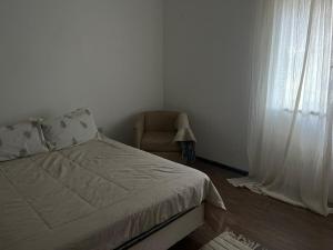 a bedroom with a bed and a chair and a window at Departamento a media cuadra de la plaza principal in Tandil