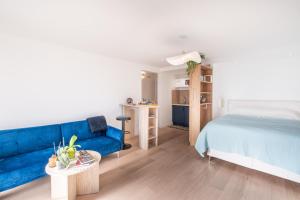 ein Wohnzimmer mit einer blauen Couch und einem Bett in der Unterkunft Appartement Poisy calme et résidentielle parking gratuit in Poisy