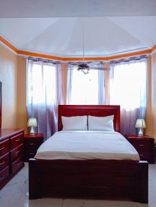 a bedroom with a large bed with two windows at Belo Résidence in Cap-Haïtien +11 photos