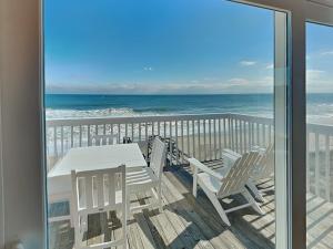a balcony with a table and chairs and the ocean at Ocean Dunes 306 in Kure Beach